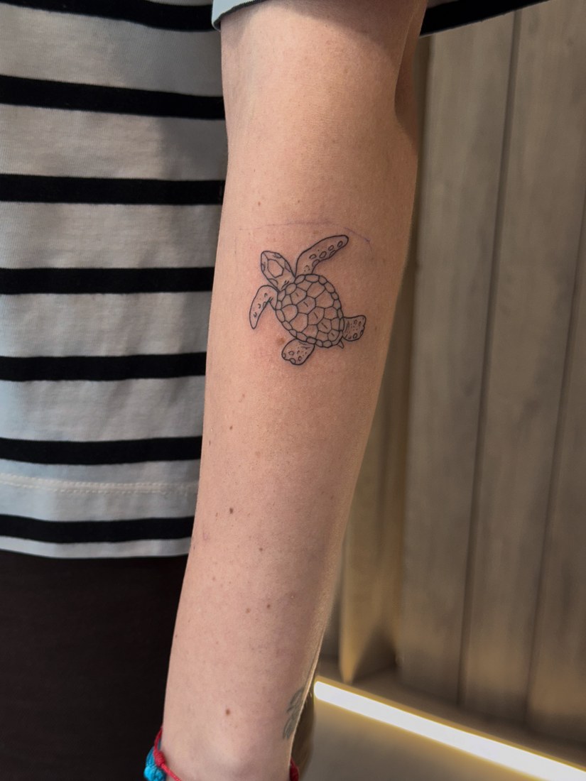 Tatuaje fine line de una luna con brújula en el antebrazo